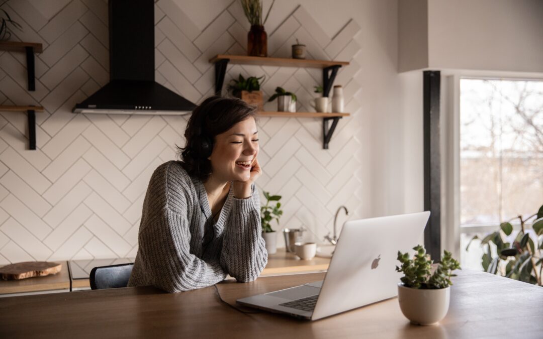 Smiling woman talking via laptop in kitchen